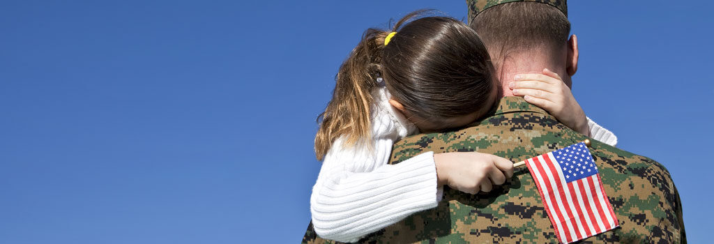 young girl holding small American Flag hugs her veteran father American VA Loans