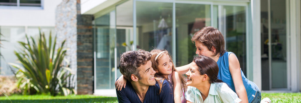 family of four sit in grass outside contemporary home American VA Loans