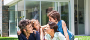 family of four sit in grass outside contemporary home American VA Loans