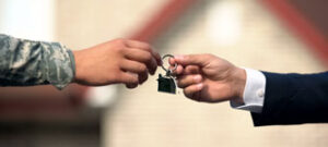 hands of military veteran and loan officer exchanging a house key American VA Loans